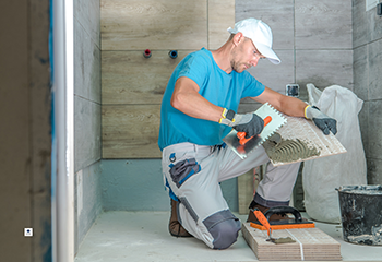 Professional worker installing marble tiles in bathroom